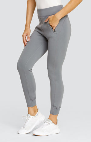 Model wearing a gray ankle length jogger with a waistband, welt pockets, and ribbed back ankle cuffs.