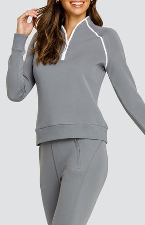 Model wearing a gray long sleeve sweatshirt with a quarter zip neckline, white piping accents, and ribbed hem and cuffs. Paired with a matching jogger with welt pockets.