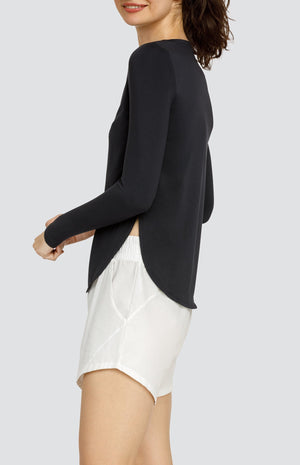 Model wearing a long sleeve top with high side slits and white shorts with elastic waistband and pockets.