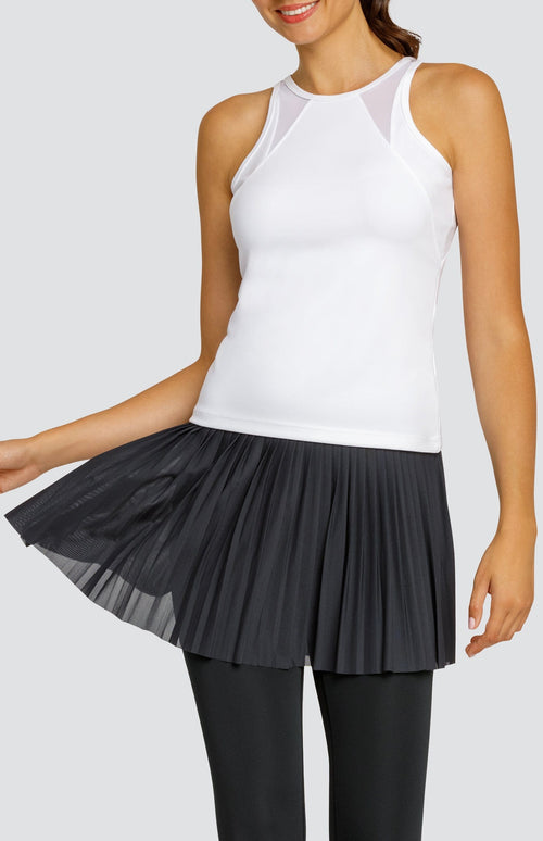 Model wearing a white high neck tank top with mesh inserts and high waisted black leggings with an attached mesh micro pleated skirt.