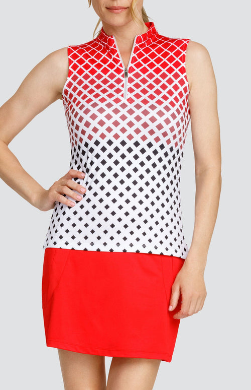 Model wearing a sleeveless golf top with a diamond ombre print, and a red skort.