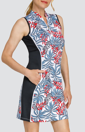 Model wearing a sleeveless golf dress with a red and blue palm frond print on a white background with black side inserts.