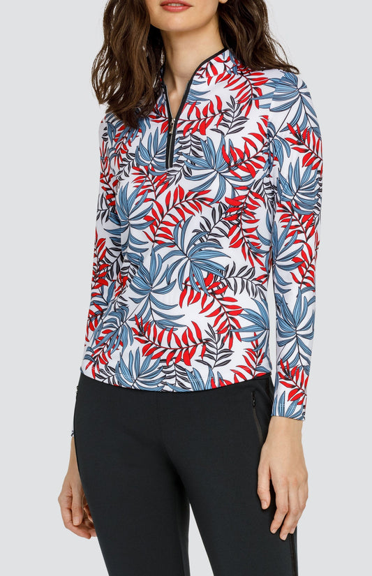 Model wearing a long sleeve golf top with red and blue fronds on a white background, and black pants.