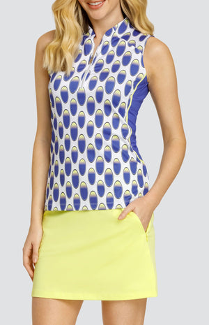 Model wearing a sleeveless top with an oval pattern in blue and yellow on a white background, and a solid yellow golf skort.