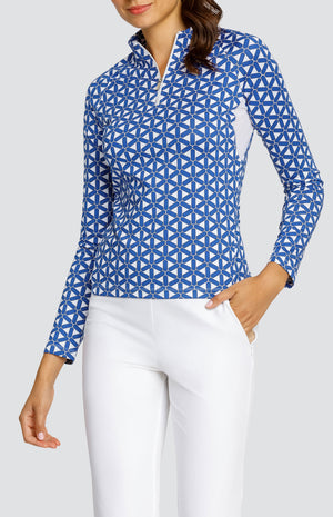 Model wearing a long sleeve golf top with a blue and white lattice pattern, and white pants.