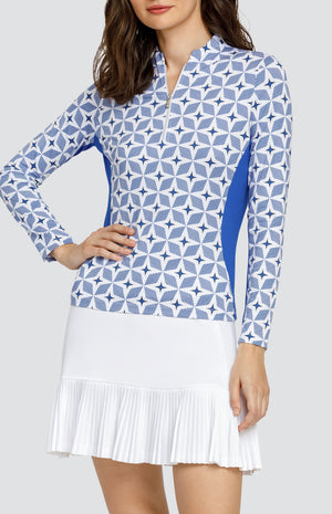 Model wearing a long sleeve golf top with a starry blue and white print and solid blue side inserts, and a solid white skort.