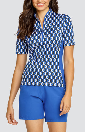 Model wearing a short sleeve blue, black, and white geometric printed top and matching blue shorts.