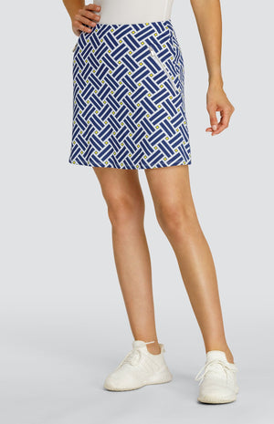 Model wearing a pull on golf skort with a criss crossing blue pattern and yellow squares on a white background.