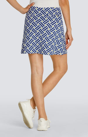 Model wearing a pull on golf skort with a criss crossing blue pattern and yellow squares on a white background.