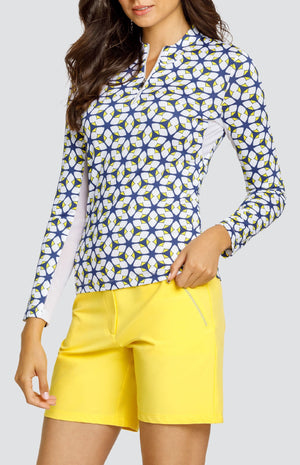 Model is wearing a long-sleeved performance jersey top in "Nova Rush" pattern. The top has Lakestorm Blue, Chalk White, and Dandelion yellow. Top has a novelty collar with a front quarter zip detailing. 