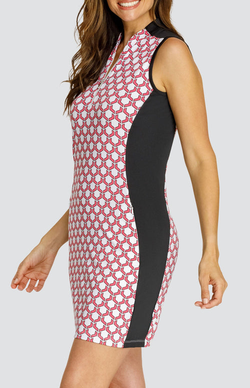 Model wearing a sleeveless quarter-zip golf dress in a pink and white geometric pattern with black side inserts.