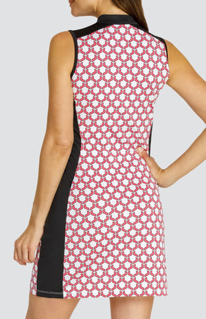 Model wearing a sleeveless quarter-zip golf dress in a pink and white geometric pattern with black side inserts.