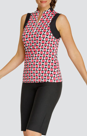 Model wearing a sleeveless quarter-zip golf top with a pink, white and black geometric pattern and black sleeve inserts, and pull on black golf shorts.