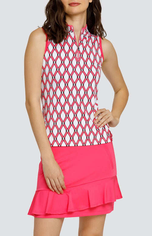 Model wearing a sleeveless quarter-zip golf top with a pink and white lattice pattern, and a pull on pink golf skort with a flounce hem.