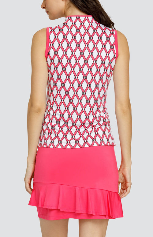 Model wearing a sleeveless quarter-zip golf top with a pink and white lattice pattern, and a pull on pink golf skort with a flounce hem.