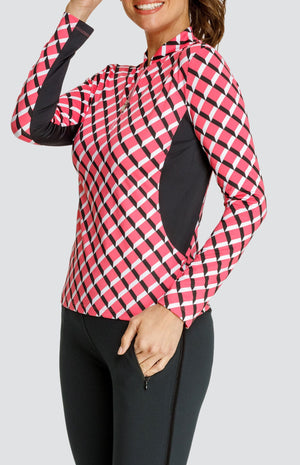 Model wearing a long sleeve quarter-zip golf top with a pink 3-dimensional block pattern and pull on black golf pants.