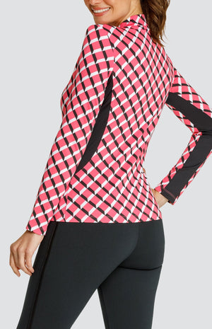 Model wearing a long sleeve quarter-zip golf top with a pink 3-dimensional block pattern and pull on black golf pants.