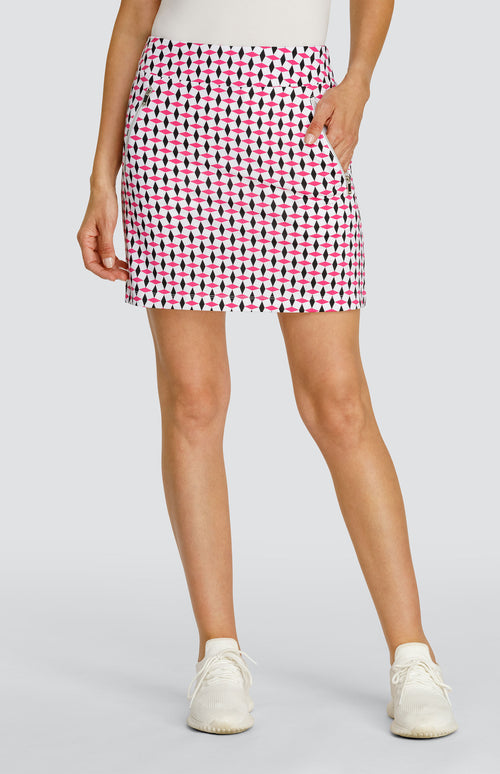 Model wearing a pull-on golf skort in a pink and black geometric alternating diamond print on a white background.