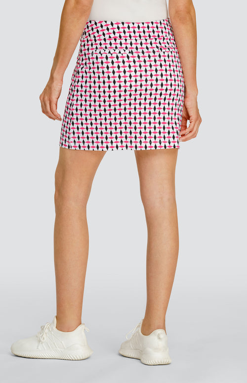 Model wearing a pull-on golf skort in a pink and black geometric alternating diamond print on a white background.