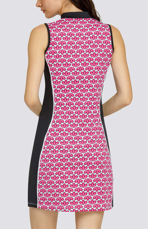 Model wearing a sleeveless quarter-zip golf dress in a pink geometric floral print on a white background with black side inserts.