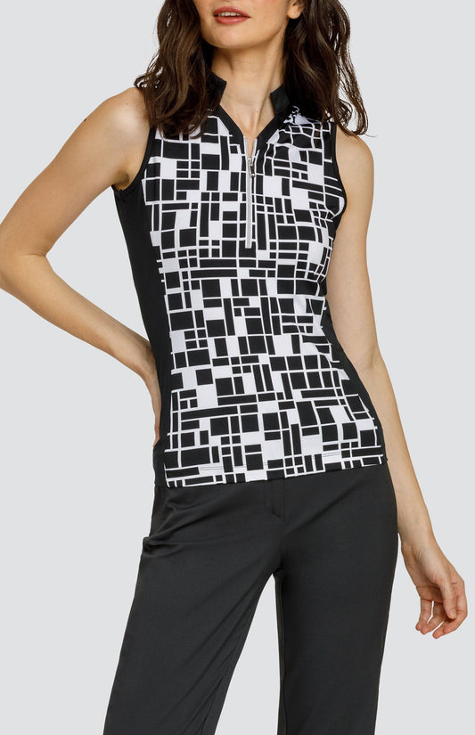 Model wearing a sleeveless black and white geometric pattern golf top and black pants.