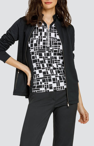 Model wearing a sleeveless black and white geometric pattern golf top, black pants and a black jacket