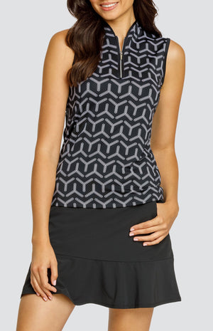 Model wearing a sleeveless golf top with a black and white geometric pattern and a black skort.