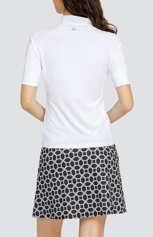 Model wearing a short sleeve white golf top and a black and white geometric print skort.