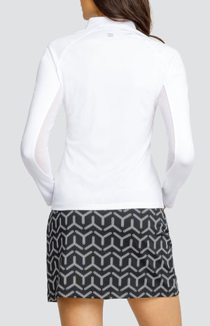 Model wearing a white raglan long sleeve golf top and a black and white geometric print skort.