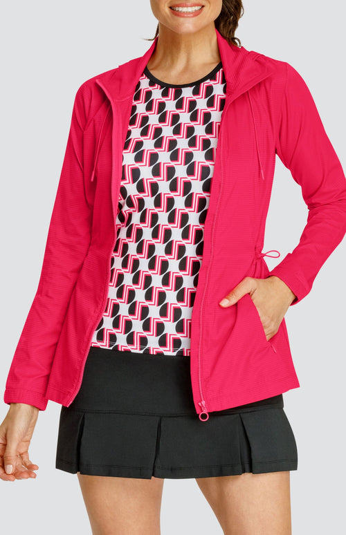 Model wearing a tennis tank with a geometric black and red pattern on a white background, and a black pleated skort, and a matching red jacket.